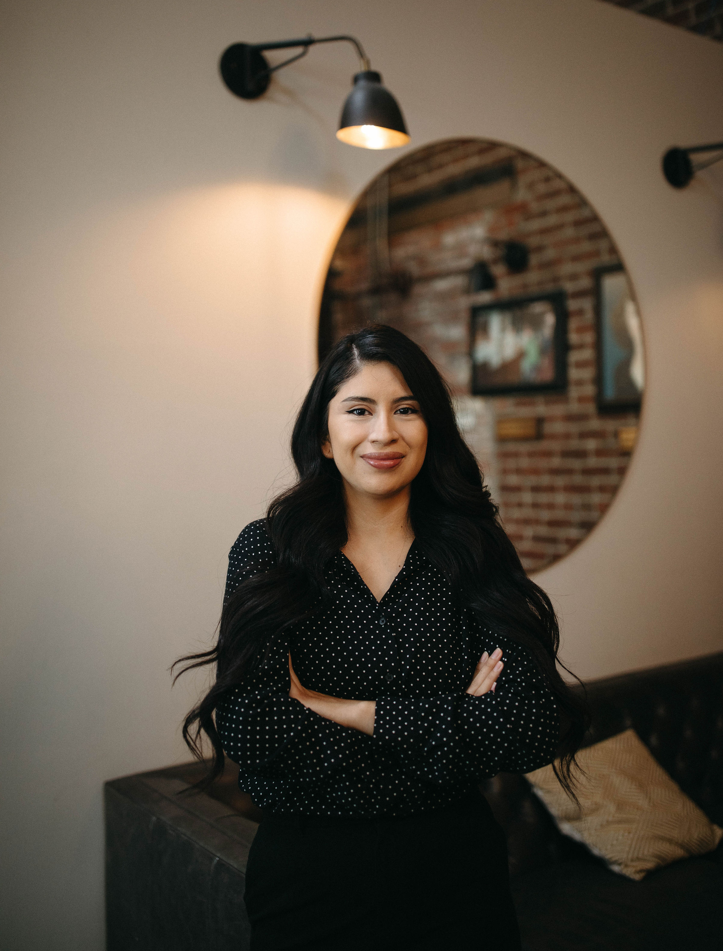 portrait of a woman wearing a black button up leaning on a brown couch